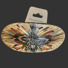 An oval birchbark hair claw clip with detailed feather work design and porcupine quills. 